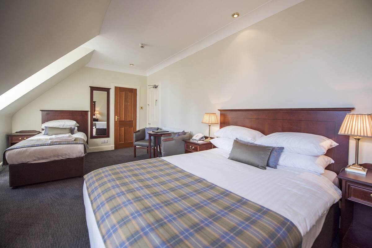 A hotel room with a large bed, a desk, a chair, and a small table.
