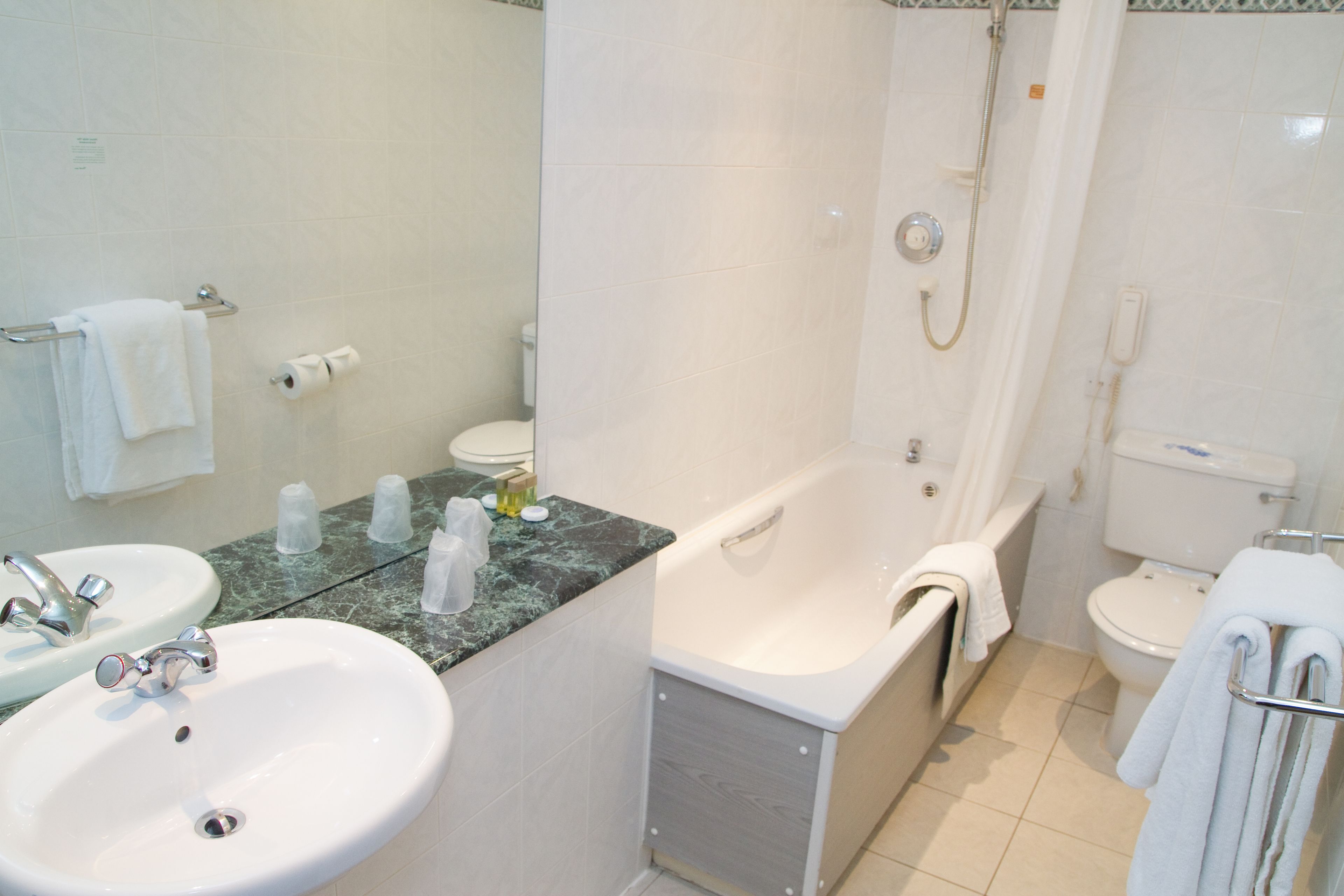A bathroom with a sink, mirror, toilet, and bathtub.