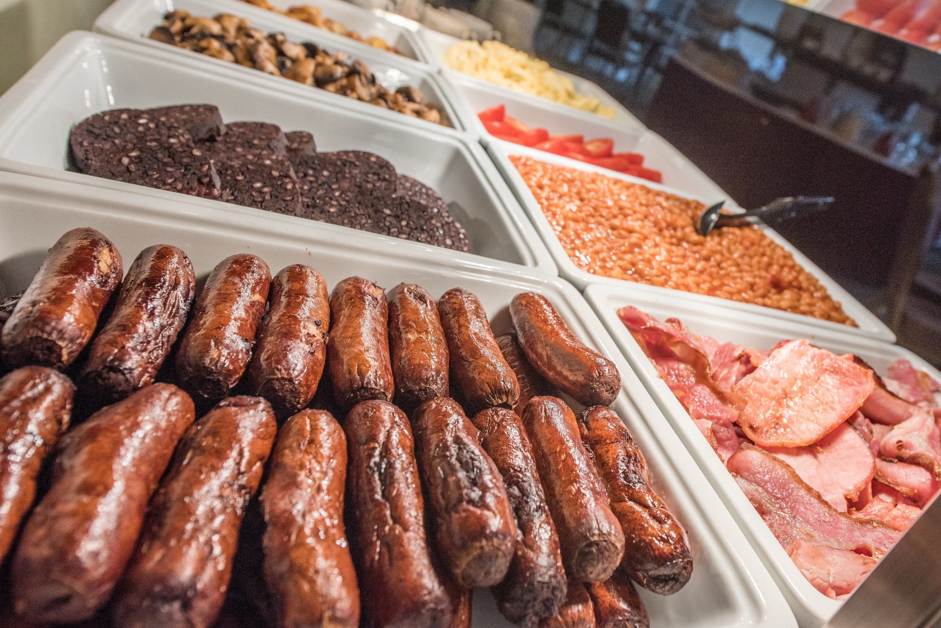 A buffet with various food items including sausages, meats, and beans.