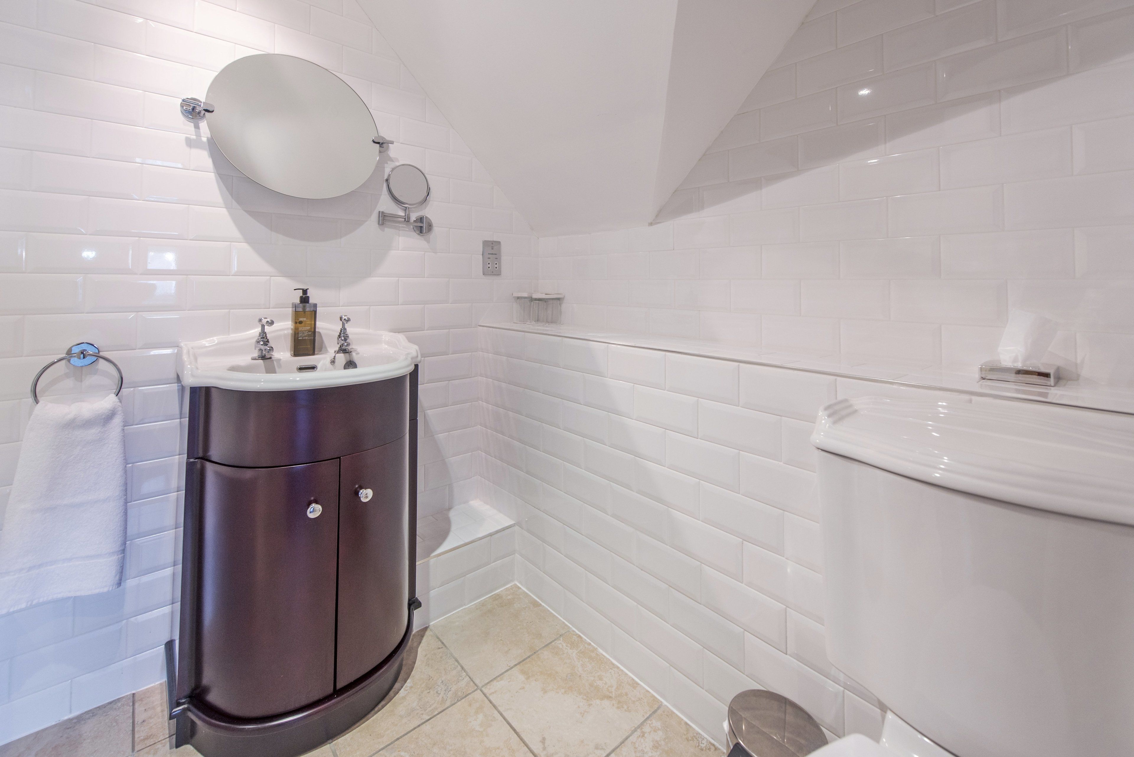 A bathroom with white subway tiles, a dark-toned vanity with a mirror, and a white toilet.