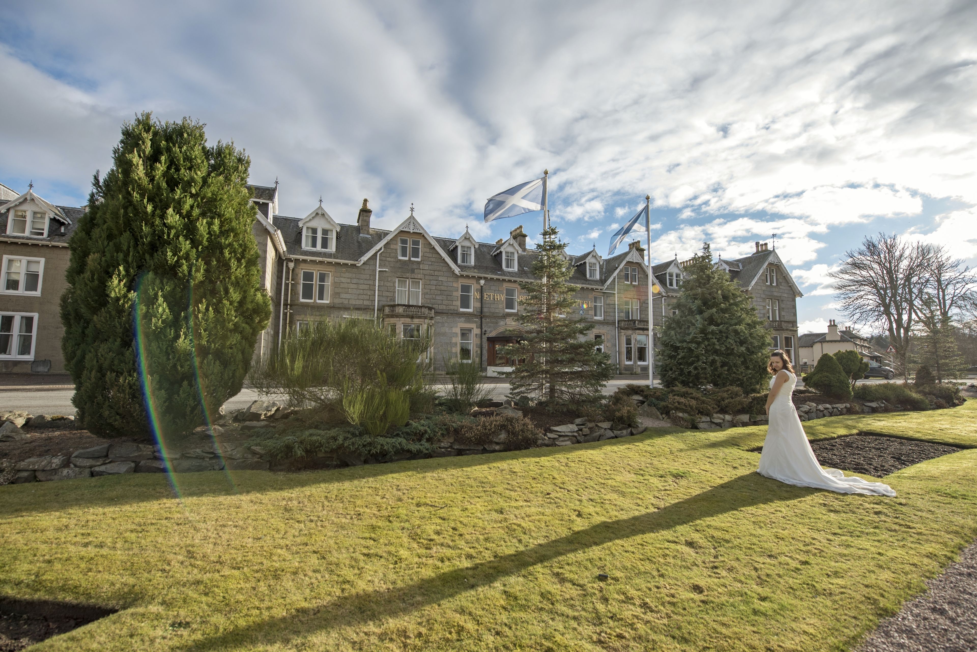 A large, historic building with multiple windows and a well-maintained lawn in front.