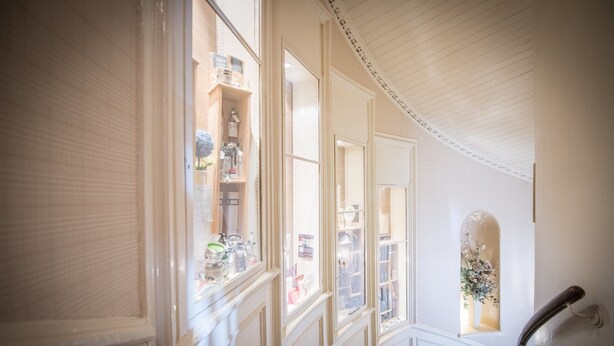 A grand staircase with ornate railings and a view of a shop through the windows. - The Royal Hotel (Oban)
