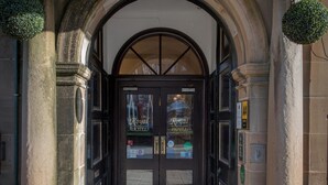 A hotel entrance with a stone archway, double doors, and a doormat. - The Royal Hotel (Oban)