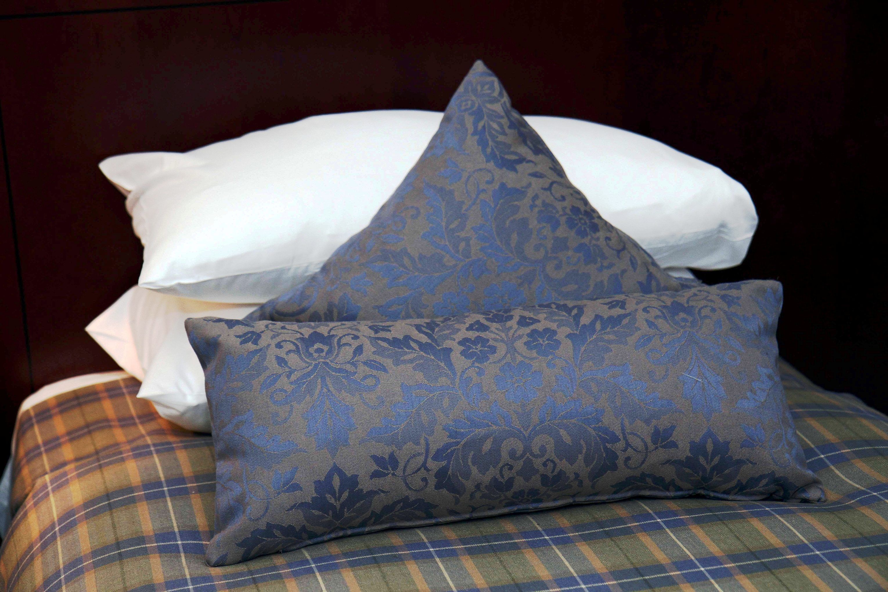 A bed with a plaid-patterned pillow and a blue floral-patterned pillow.