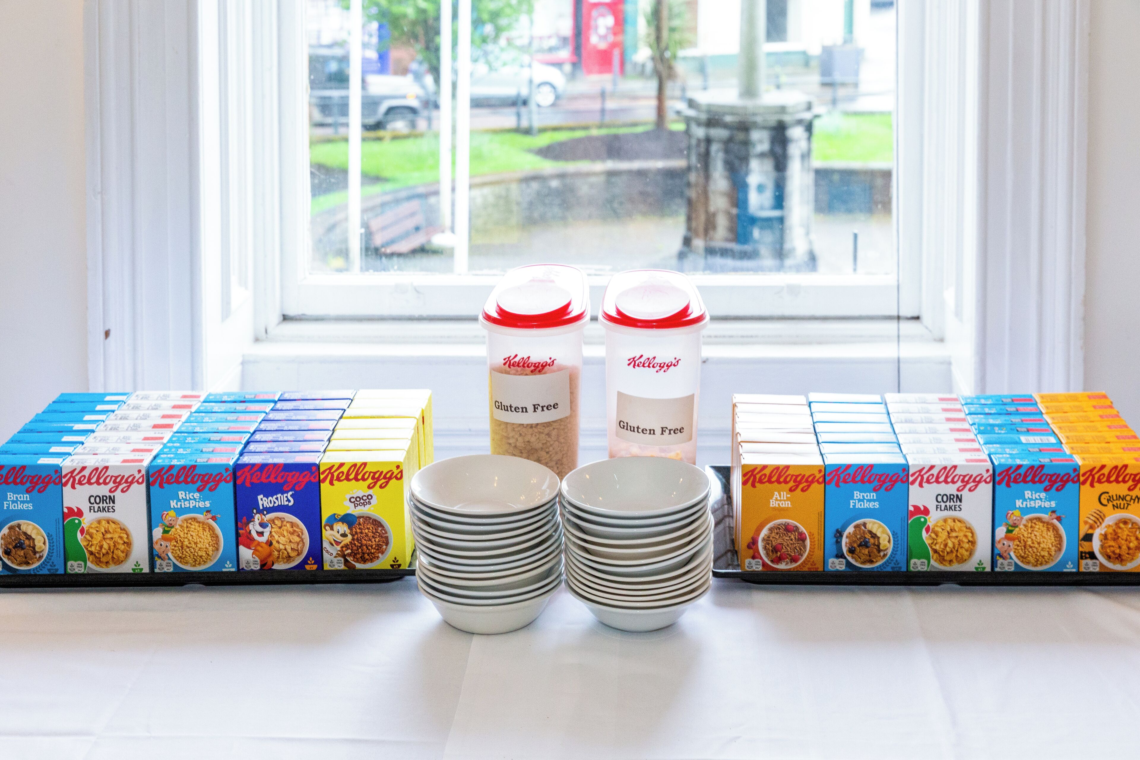 A breakfast buffet with various cereal boxes and bowls of cereal.