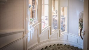 A staircase with a view of a room with a window and a door. - The Royal Hotel (Oban)
