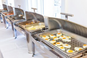 Una barra de buffet con diferentes estaciones de comida, incluyendo una bandeja de huevos fritos.