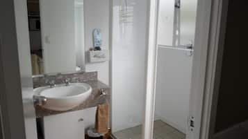 A bathroom with a white sink, a mirror, a towel rack, and a glass shower enclosure.