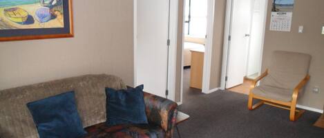 A living room with a patterned sofa, a wooden chair, and a framed painting.