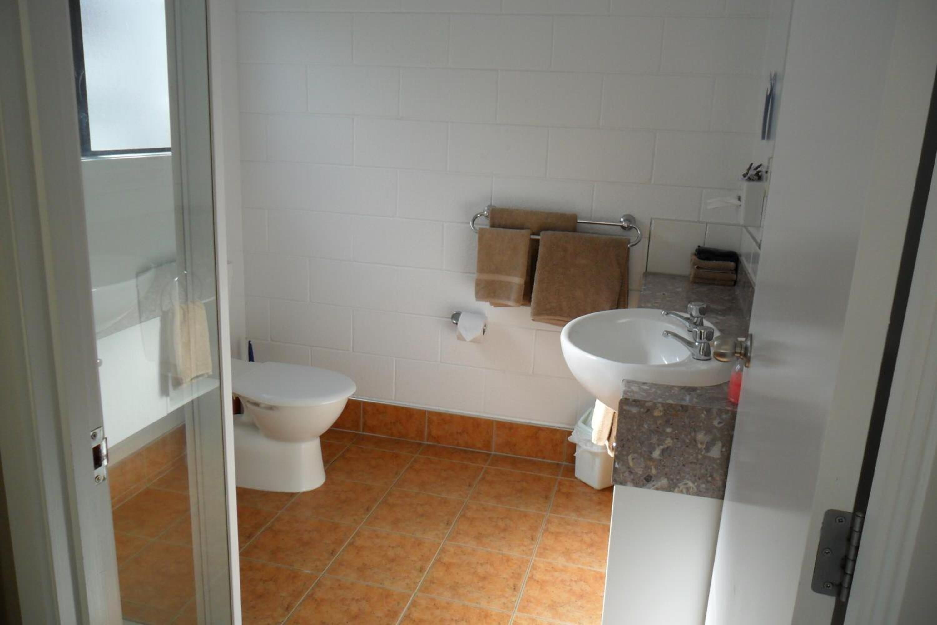 A bathroom with a toilet, sink, and towel rack.