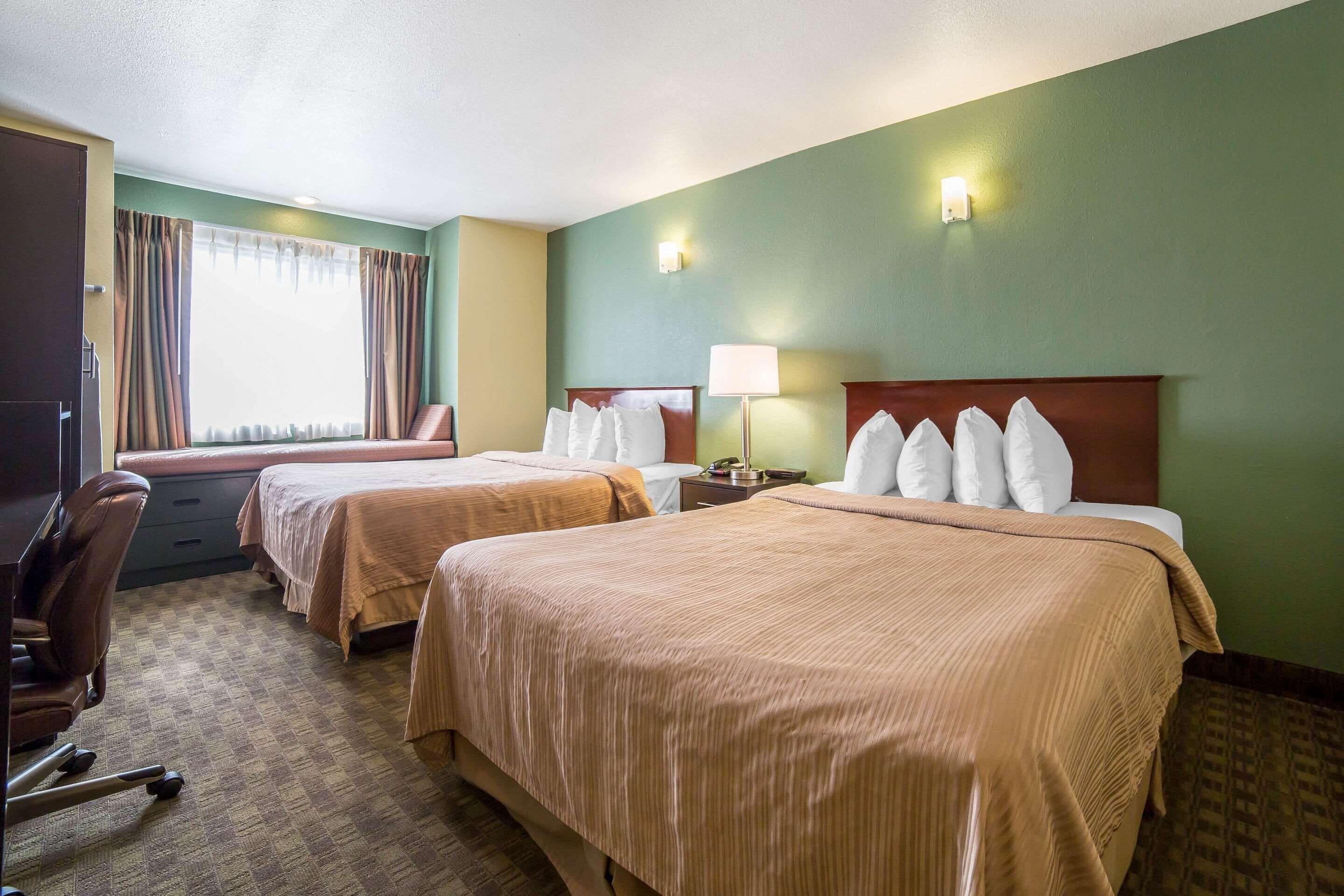 Een hotelkamer met twee bedden, een bureau en een stoel.