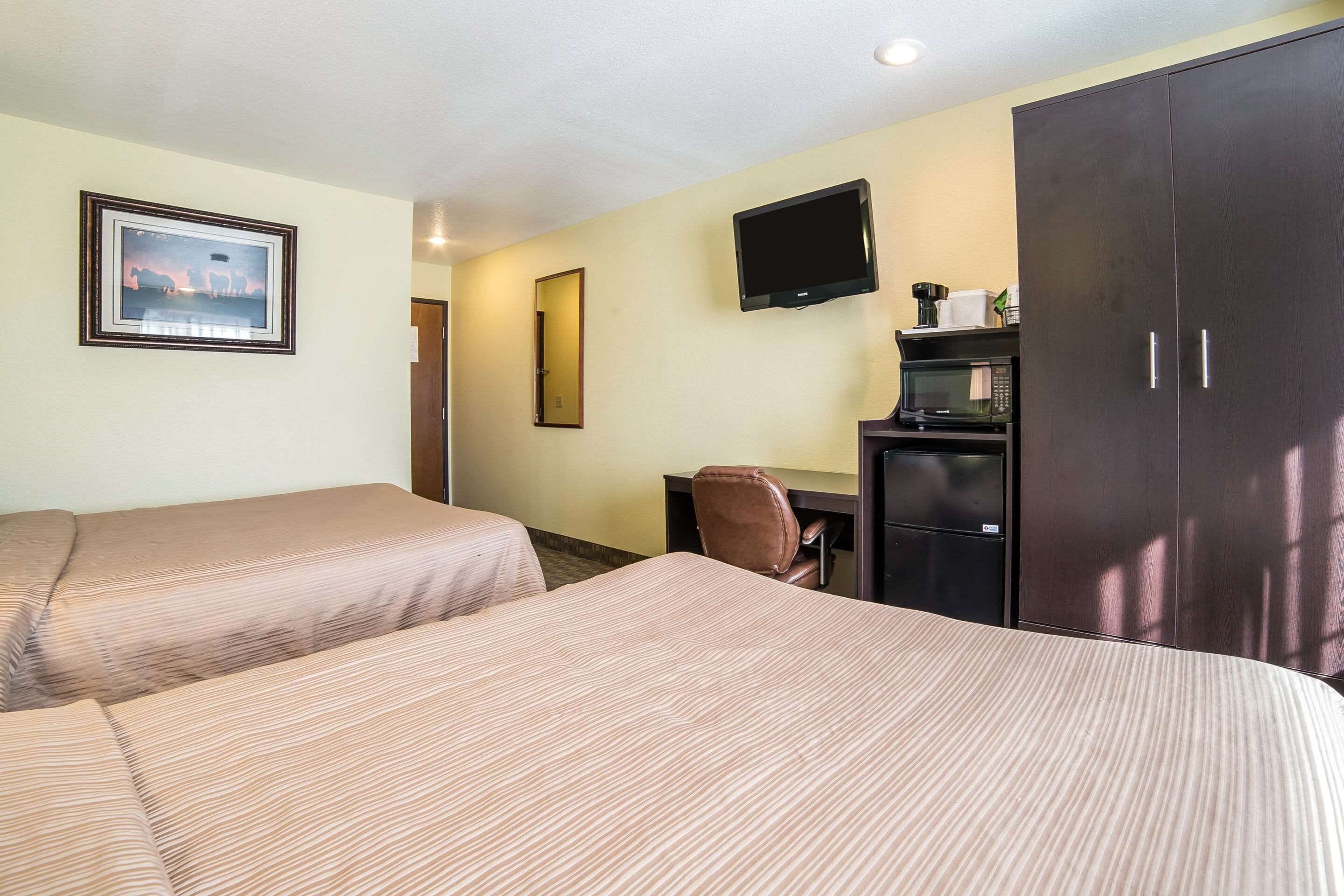 A hotel room with two beds, a desk, a television, and a wardrobe.