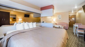 A hotel room with a large bed, a desk, a chair, a sofa, a flat-screen TV, and a bathroom with a mirror and sink. - Quality Inn & Suites Elko (Elko)