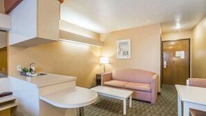 A compact hotel room with a kitchenette, a sofa, a small table, and a lamp. - Quality Inn & Suites Elko (Elko)
