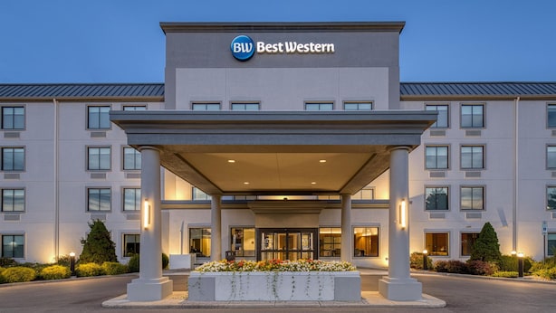 A Best Western hotel entrance with a covered entrance, large windows, and a landscaped area with flowers. - Best Western Byron Center (Byron Center)