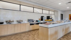 A modern kitchen with a central island, wooden cabinets, and a tiled backsplash. - Best Western Byron Center (Byron Center)
