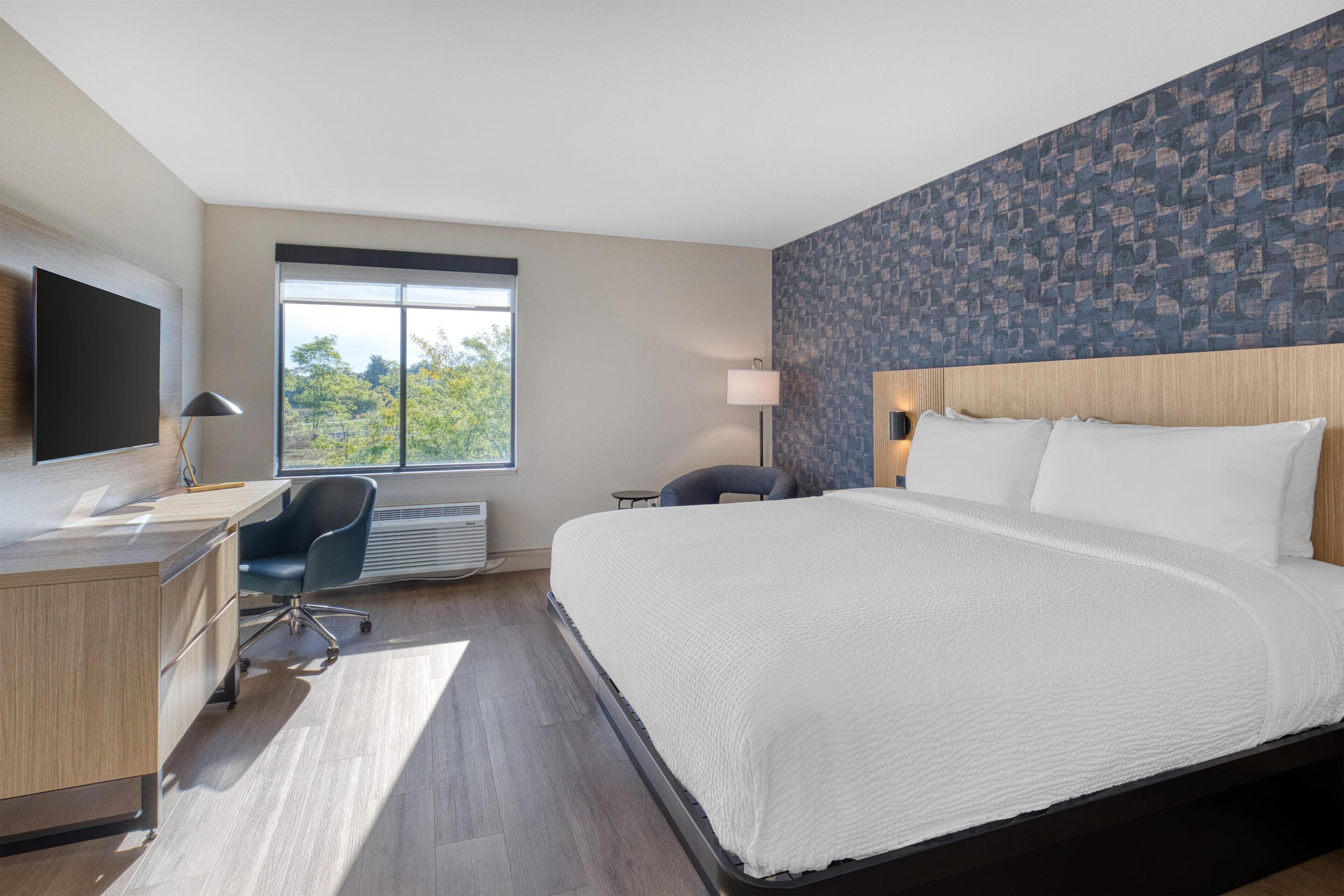 Een moderne hotelkamer met een groot bed, een bureau, een stoel en een televisie.