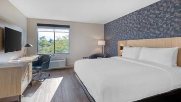 Een moderne hotelkamer met een groot bed, een bureau, een stoel en een televisie.
