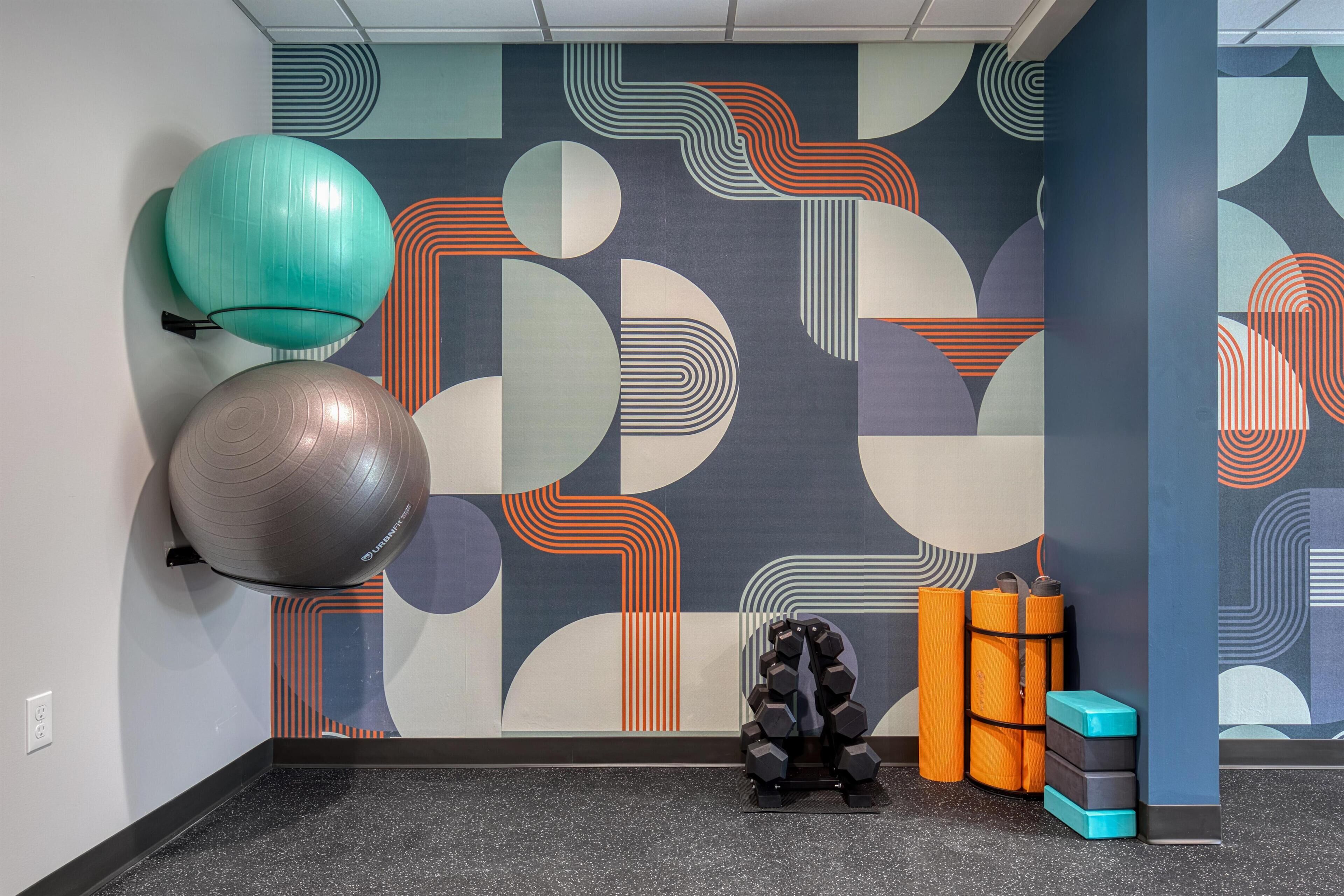 A gym with exercise equipment and a patterned wall.