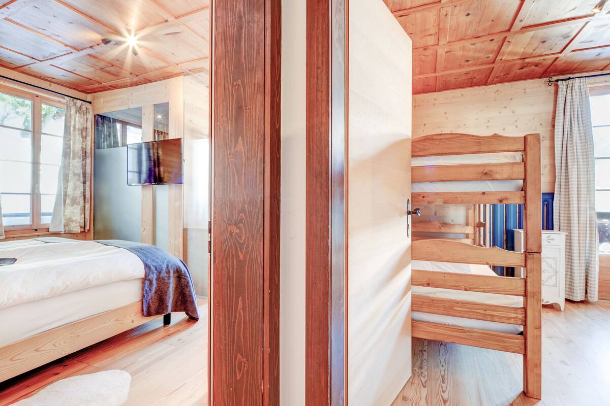 Ein Holzhütten-Zimmer mit einem Bett, einem Fernseher und einem Fenster mit Vorhängen.