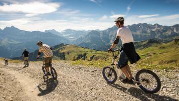Un groupe de personnes fait du vélo sur un chemin de gravier, avec un paysage montagneux en arrière-plan.