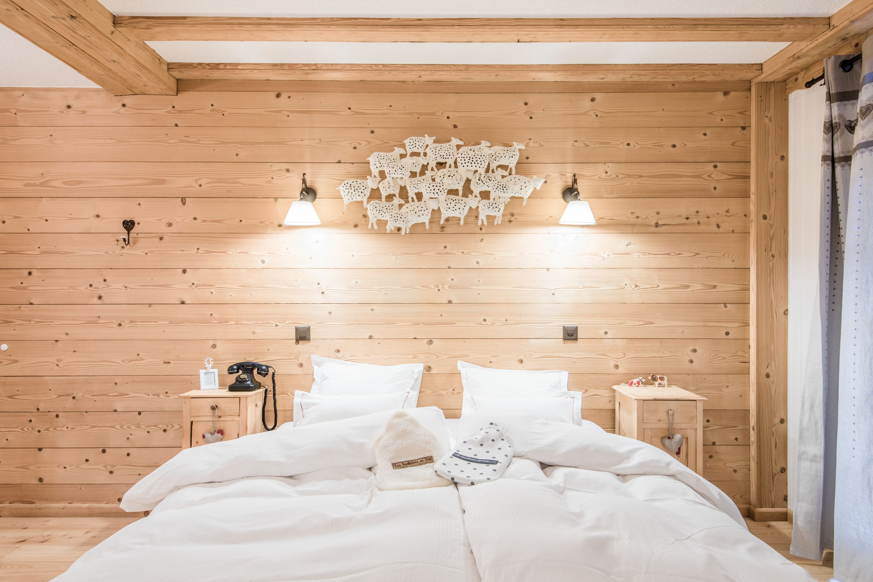 A wooden-paneled room with a bed, two bedside tables, and a wall decoration.
