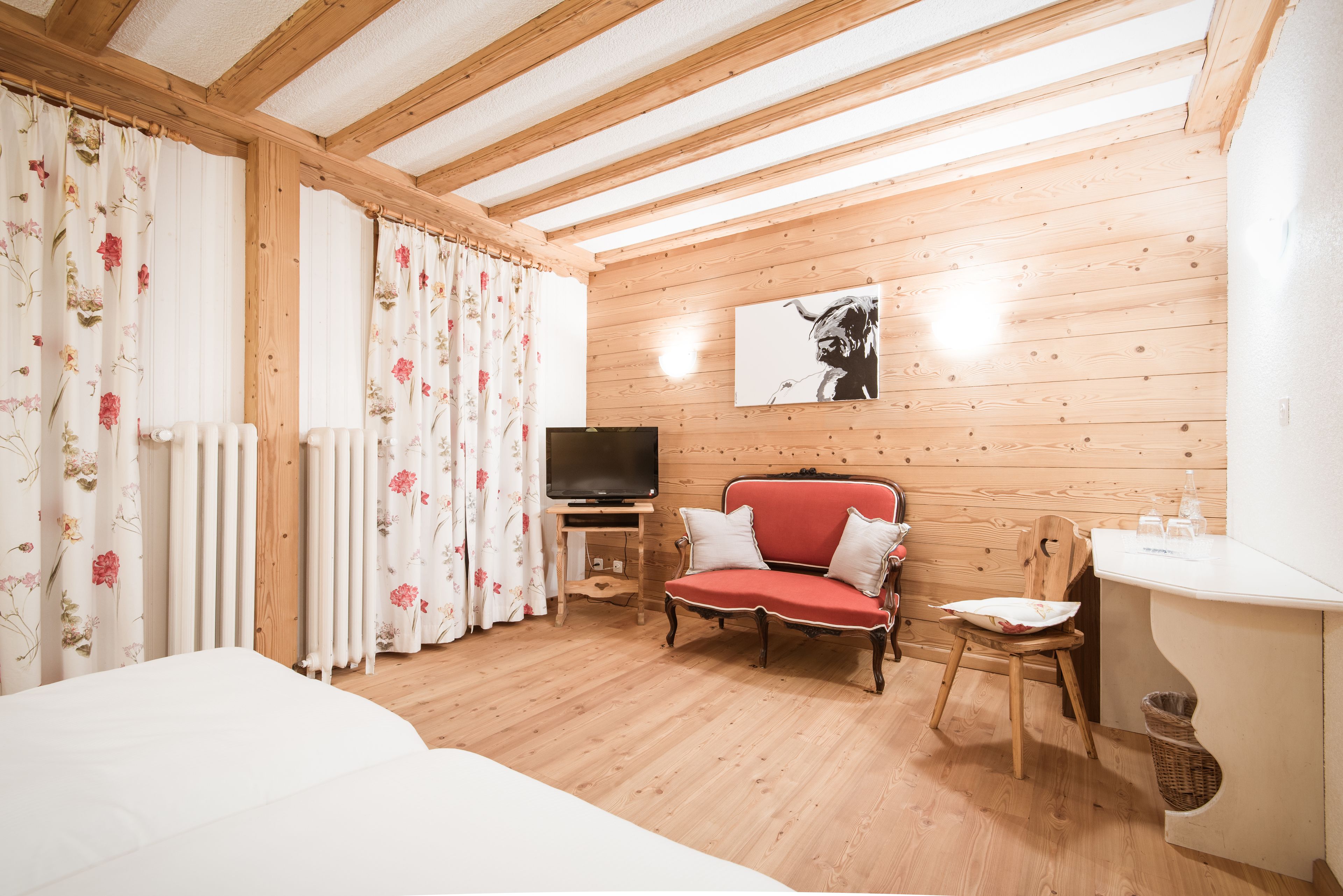 Una habitación acogedora con paredes de madera, un sofá rojo, un televisor y una silla de madera.