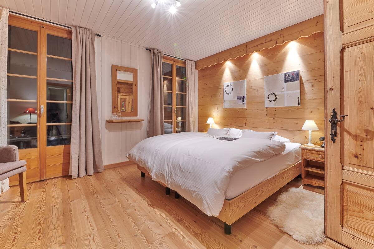 Ein Schlafzimmer mit Holzwänden, einem Bett, Nachttischen und einem Kleiderschrank.