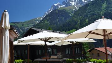 Un espace extérieur aménagé avec des tables, des chaises, des parasols et une vue sur la montagne.