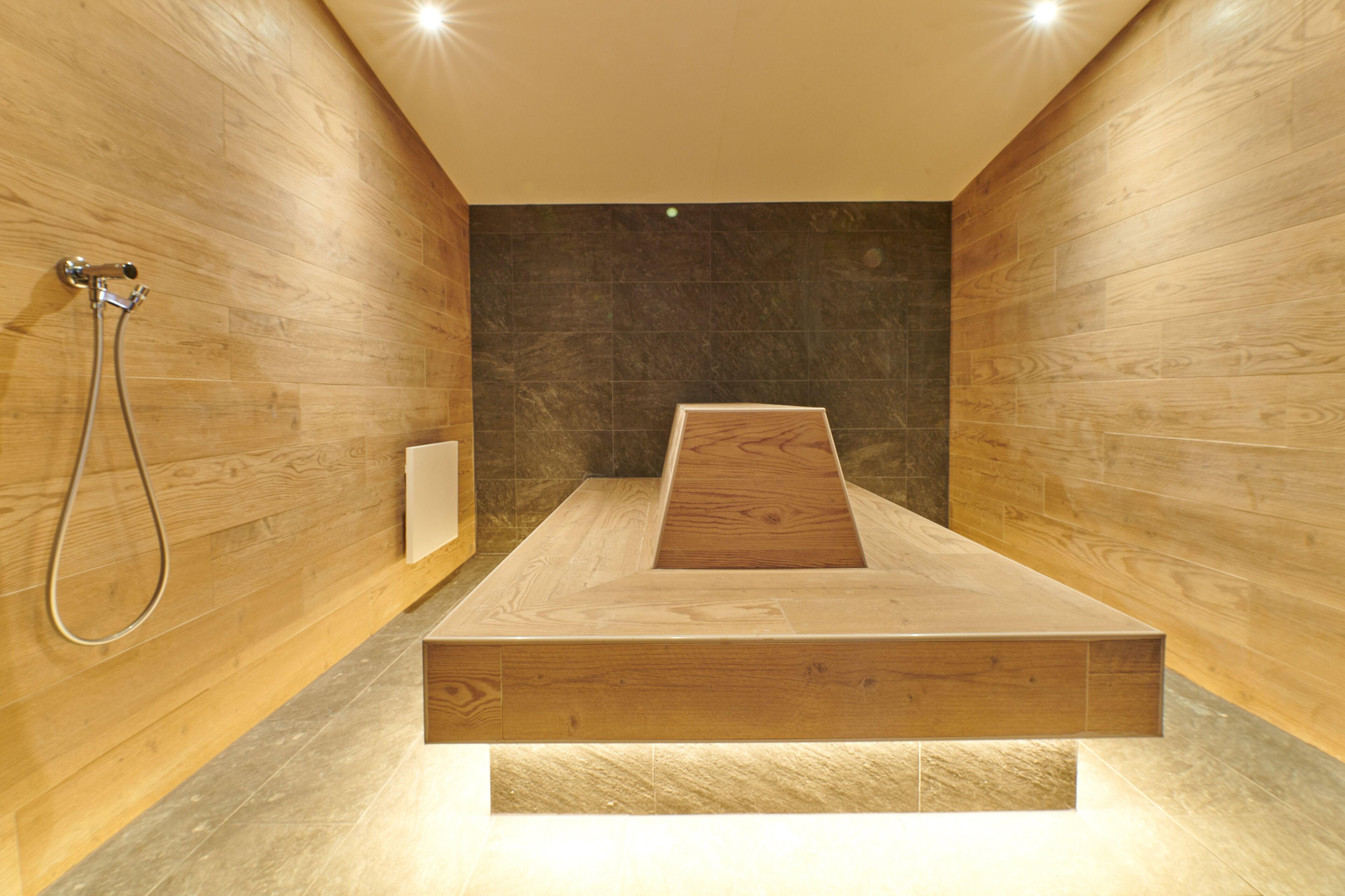 Un área de ducha moderna con un banco de madera y un cabezal de ducha.