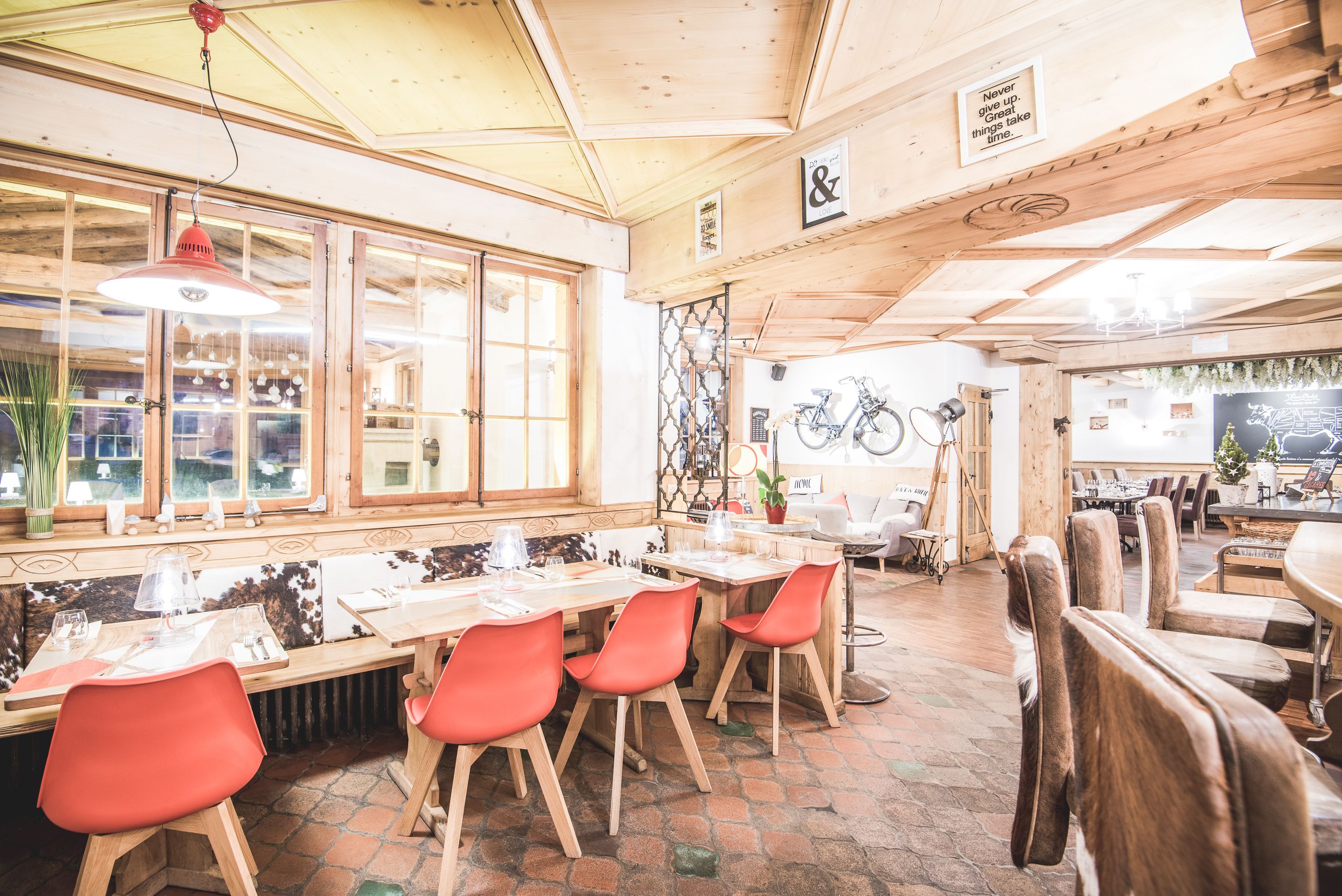 Een restaurant met houten inrichting, rode stoelen en een fiets op de achtergrond.