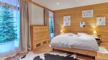 Une chambre à coucher aux murs lambrissés, avec un lit, deux lampes de chevet et des œuvres d’art accrochées au mur.