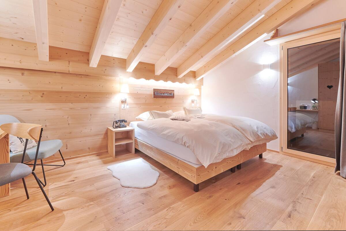 Ein Schlafzimmer aus Holz mit einem Bett, Nachttischen und einem Sessel.