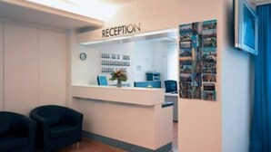 Un espace d’accueil comprenant un comptoir de réception, une horloge et un mur orné de tableaux.