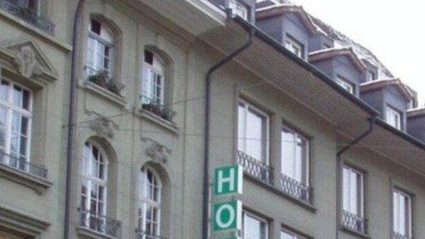 Un immeuble à plusieurs étages, reconnaissable à son grand panneau vert indiquant qu’il s’agit d’un hôtel.