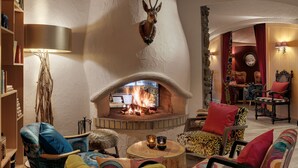 Een gezellige woonkamer met een open haard, diverse meubels en een stenen muur.