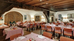 A restaurant with multiple tables set for dining, featuring a rustic interior with wooden beams and arches.