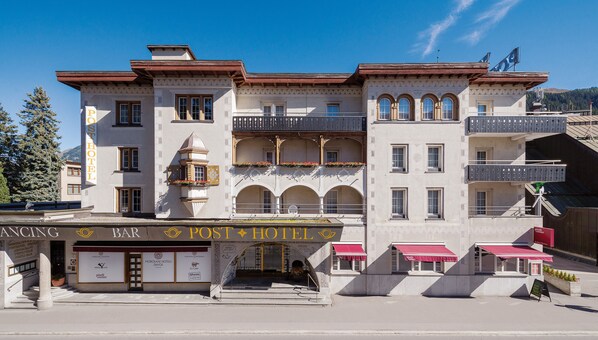 A hotel with a bar and restaurant at the ground level, featuring a traditional architectural style with arched windows and balconies.