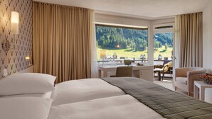 Een hotelkamer met een bed, een bureau en uitzicht op een bergachtig landschap.