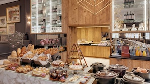 A buffet area with various food items, a wine and liquor display, and a mirror reflecting the space. - Morosani Schweizerhof (Davos)