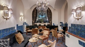 A luxurious lobby with a chandelier, seating area, and decorative wall sconces. - Morosani Schweizerhof (Davos)