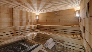 Una sauna con bancos de madera, una bañera de hidromasaje de piedra y toallas.