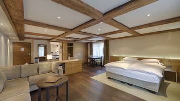 Habitación de hotel moderna con techo de madera, cama grande, sofá, escritorio y una mesita.