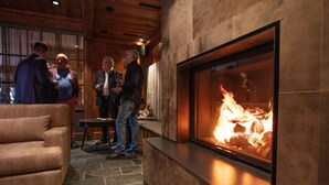 Un interior moderno con una chimenea de piedra, un sofá y un grupo de personas conversando.