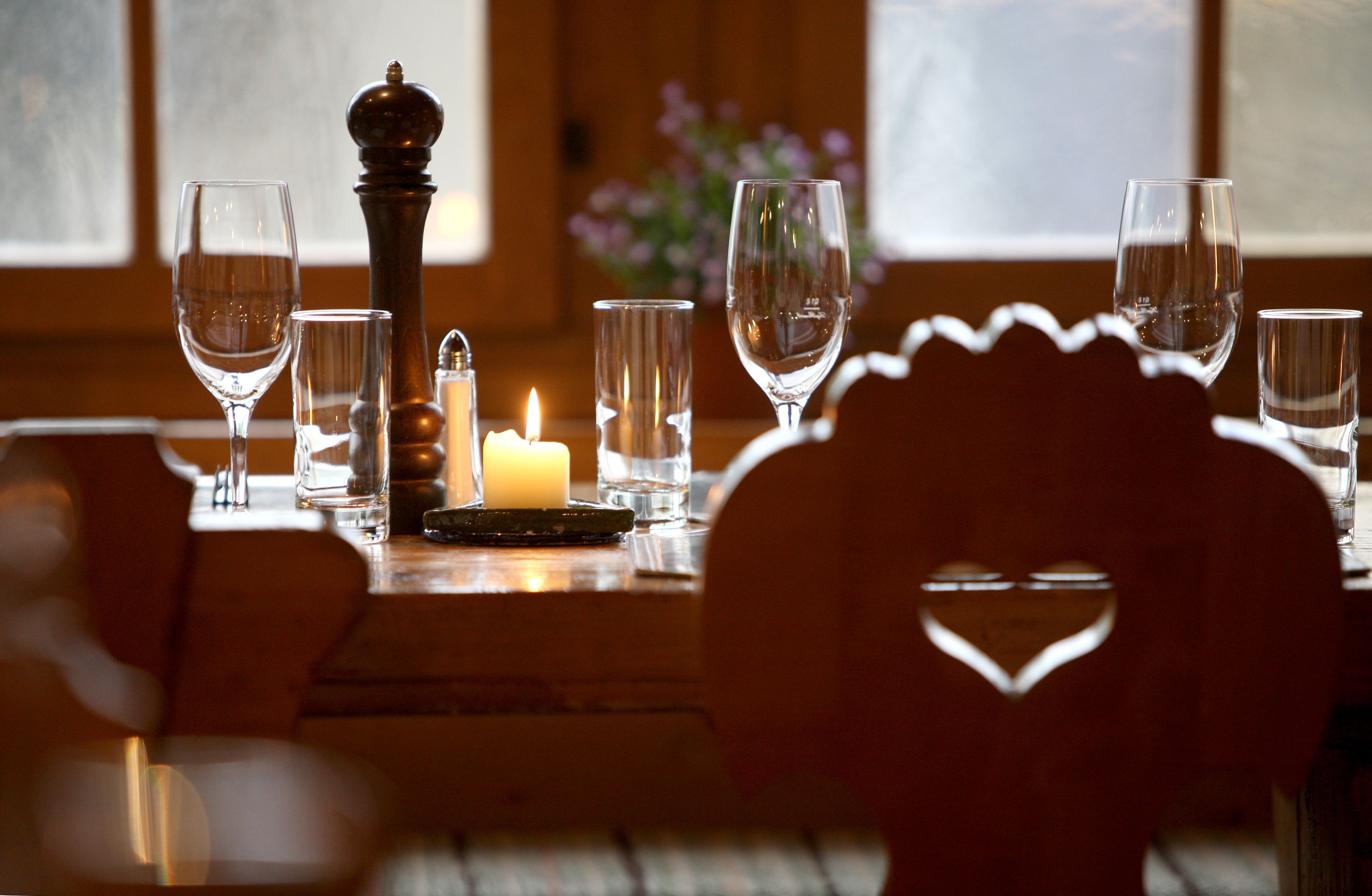 Una mesa de comedor con seis copas de vino, una vela y un salero.