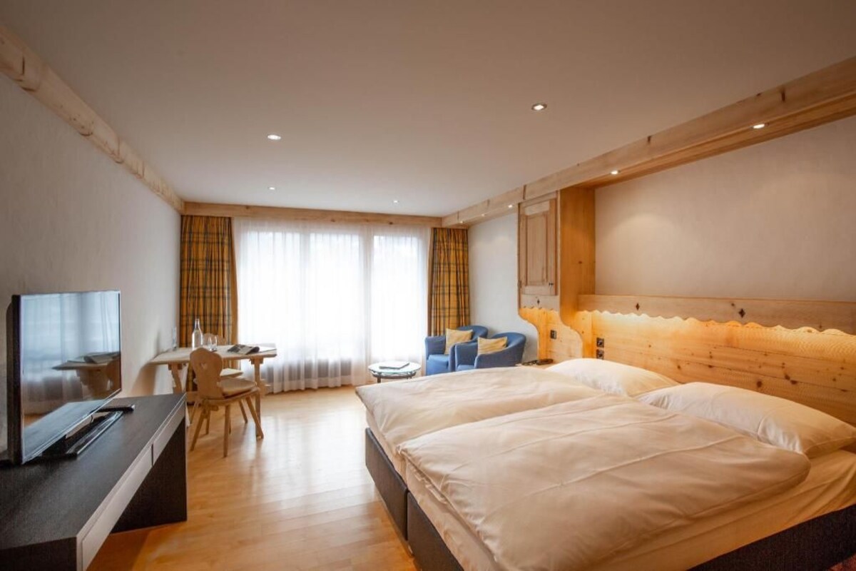 A hotel room with a bed, a TV, a desk, and a chair.