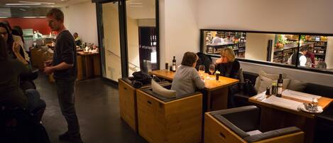 A modern restaurant with wooden seating, a bar area, and a view of the street through large windows.