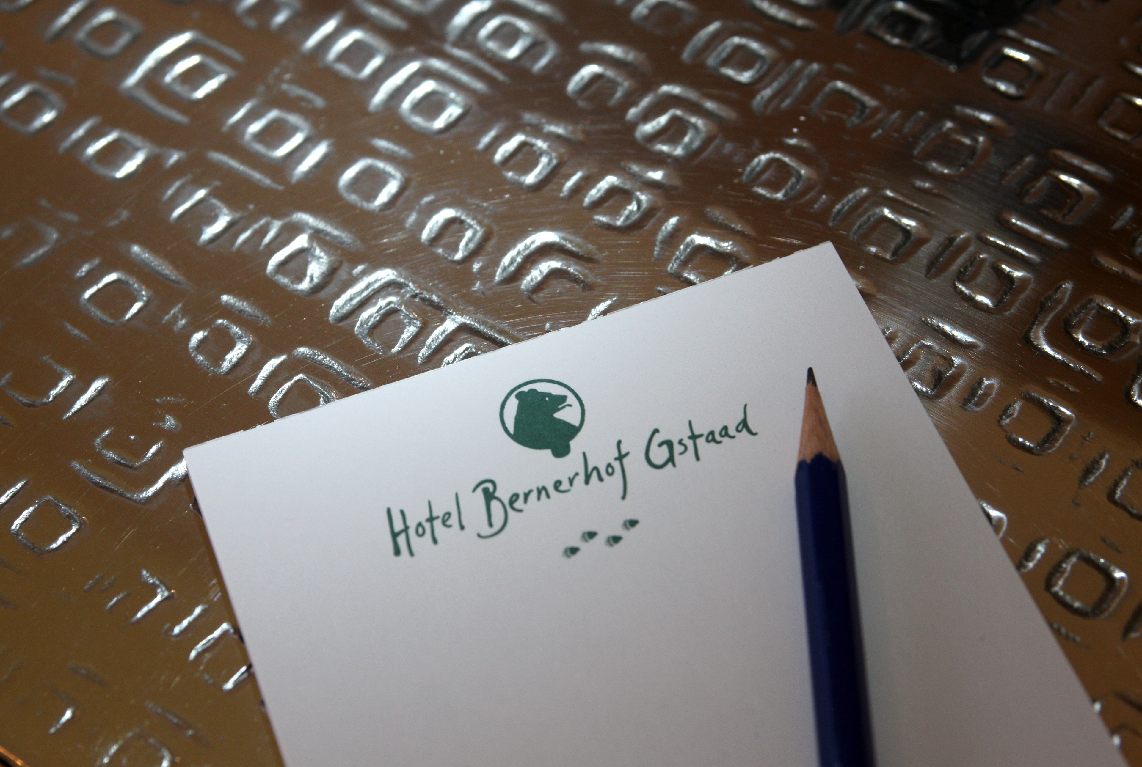 A piece of paper with the text "Hotel Bernerhof Gstaad" and a logo, placed on a textured surface.