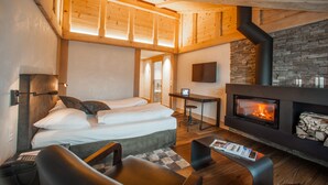 Una habitación de hotel con cama, escritorio, chimenea y televisor montado en la pared.