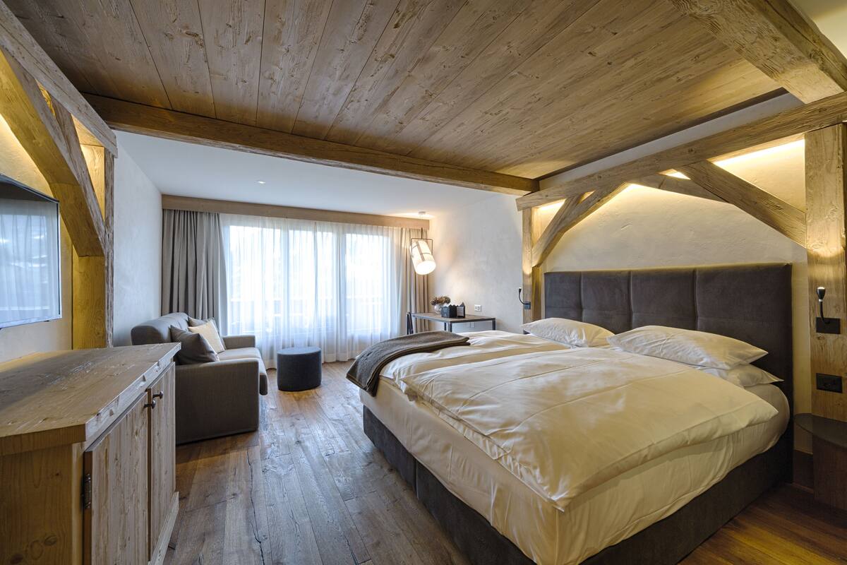 Un dormitorio amplio con una cama grande, techo de madera, un sofá y un escritorio.